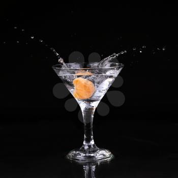 martini cocktail splashing into glass on black background