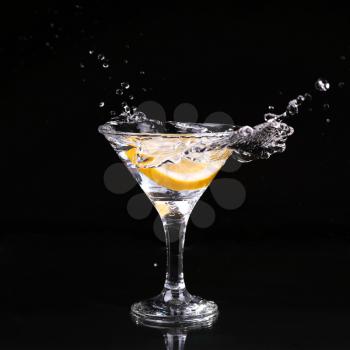 martini cocktail splashing into glass on black background