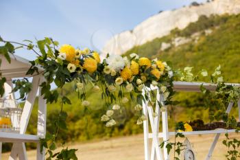 Happy outdoor Wedding Ceremony Scene for a summer mountain wedding. Wedding aisle, decorated wedding alter and flower decorations with mountains in the background. Wedding color pear
