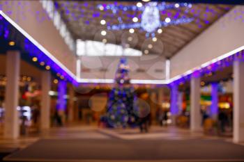 Giant Christmas tree in shopping mall. Blurred background. Christmas tree with gold decoration in shopping mall.Christmas clearance sales at the shopping mall. Elegant Christmas tree in a shopping mal