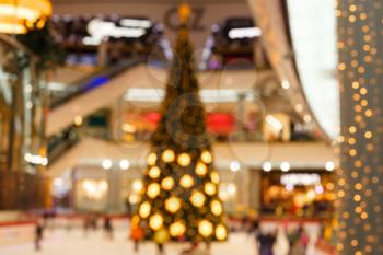 Giant Christmas tree in shopping mall. Blurred background. Christmas tree with gold decoration in shopping mall.Christmas clearance sales at the shopping mall. Elegant Christmas tree in a shopping mal