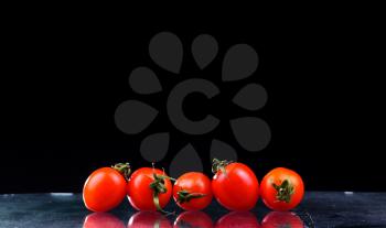 Studio shot with freeze motion of cherry tomatoes in water splash on black background with copy space