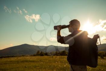 Young Man use of the binocular at forest. Tourist Camping
