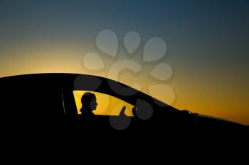 Silhouette of sedan car with girl on the background of beautiful sunset
