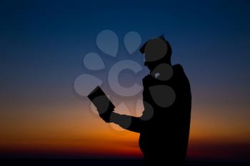 Man reading in the field against sunset