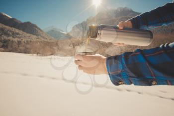 Man holding a thermos in on a snowy mountain