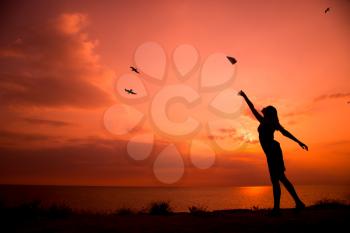 Beautiful silhouette of young woman throwing paper airplane.