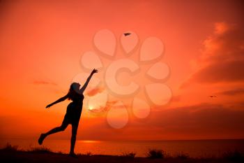 Beautiful silhouette of young woman throwing paper airplane.