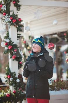 happy young woman in ski goggles outdoors. winter vacation concept. Christmas decorations in a small ski resort. Rest after successful skiing competition.