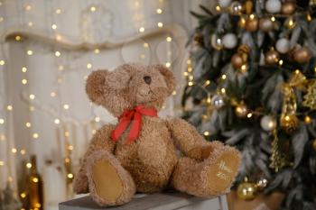 Decorated Christmas tree with various gifts. Christmas and New Year celebration. Holiday Christmas scene. Soft teddy bear sits on the background of a Christmas tree