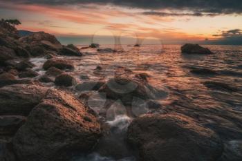 Long exposure of sea and rocks. Wispy Sunset taken with long shutter speed to show motion blur