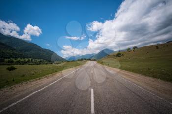 Empty asphalt road highway in the forested mountains, on the background a cloudy sky. North Caucasus, Dombay