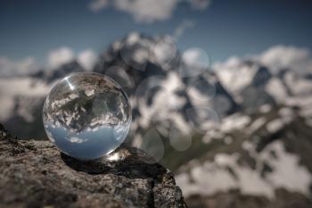 Transparent glass sphere and snow-capped peaks in the background. Concept and idea of travel