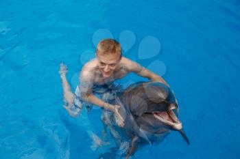 happy man swim with dolphin in dolphinarium
