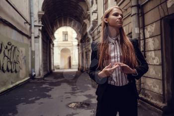A young red-haired girl in a business suit is walking along a beautiful old town. St.Petersburg