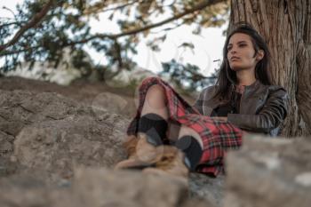 Young woman sitting on cliff and enjoy the view. A girl in a kilt, a Scandinavian mood. Crimea, Mount Cat