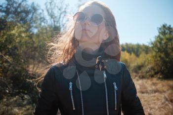 redhair woman with leather jacket surrounded of fall almond trees
