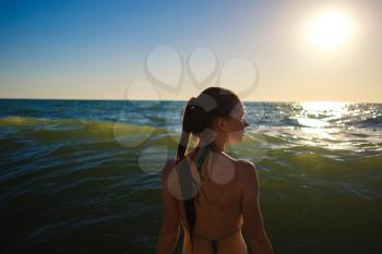 young slim beautiful woman on sunset beach, playful, dancing, running, bohemian outfit, indie style, summer vacation, sunny, having fun, positive mood, romantic, splashing water, silhouette, happy, photo toned
