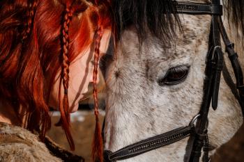 Red-haired woman with a faithful horse preparing for battle