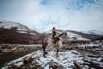 Beautiful girl on horse and with red hair in armor. Woman is a Viking. Fantasy