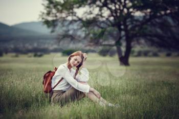 Young red-haired traveler in fairy-tale beautiful scenery. The idea and concept of rest, relaxation, freedom