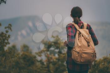 Hipster young girl with backpack enjoying sunset on peak of foggy mountain. Tourist traveler on background view mockup.