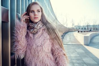 A young gorgeous woman on a walk through the sunny winter park. Near the stadium in Krasnodar, Russia.