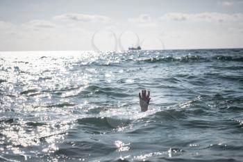 single hand of drowning man in sea asking for help. sticking out of the water