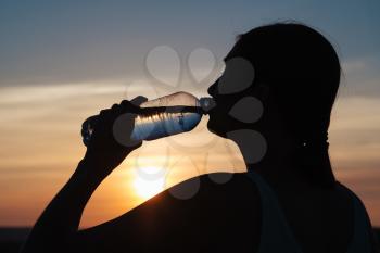 Rehydrate your body. Sporty woman drinking water outdoor on sunny day.