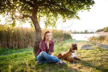 jouful young girl caressing their dog, wearing sport clothing, enjoying their time and vacation in sunny park