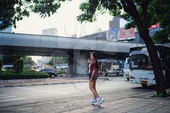 Summer sunny lifestyle portrait of young stylish hipster woman walking on the street, wearing cute trendy outfit. Young Asian women tourist traveler smiling in bangkok. street fashion