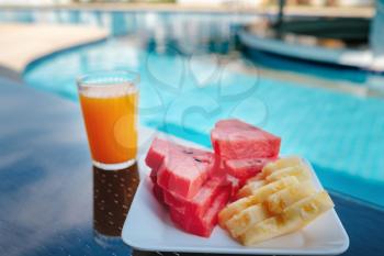 Food Plater with fruits on vacation at the swimming pool. Breakfast by the pool. pineapple, watermelon and orange juice