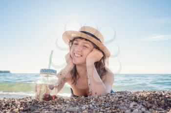 Pretty young woman drinking cocktail on the beach. Attractive girl offering a drink. Beautiful woman drinking lemonade