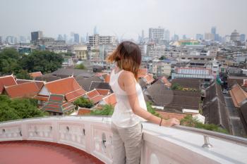 Girl admires the view from the Golden Mount, Thailand. Bangkok City panorama with skyscrapers of business district from Golden Mountain Wat Saket roof