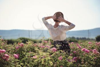 Flower series, free time of summer Provence, books reading at sunset for a bottle of red wine. young woman walking near blooming rose bushes.