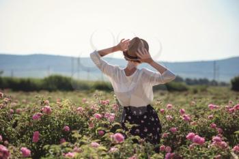 Flower series, free time of summer Provence, books reading at sunset for a bottle of red wine. young woman walking near blooming rose bushes.