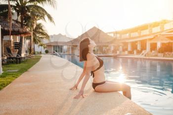 summer holidays in luxury hotel, woman relaxing near beautiful swimming pool. Beauty and body care.
