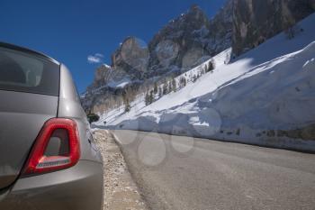 Road and car and Alpine mountains on the background. May trip to South Tyrol in the Dolomites, Northern Italy, snow mountains