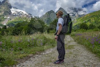 Male tourist begins his journey to the mountains on the background of the North Caucasus. Travel sport lifestyle concept. Adventure and travel in the mountains region in the Caucasus.