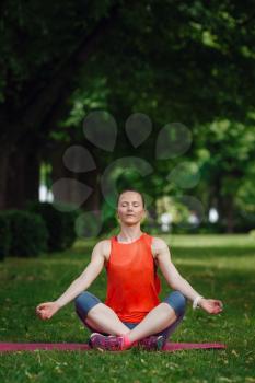 Young beautiful woman meditates on a summer day in the park. Idea and concept of calm in a busy city and a healthy lifestyle