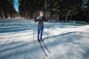 Cross-country skiing woman doing classic nordic cross country skiing in trail tracks in snow covered forest. Training track for skiers in the park of Moscow, Odintsovo