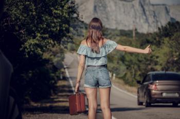 Young beautiful Asian woman in hippy style. travels by hitchhiking. Road in the mountains