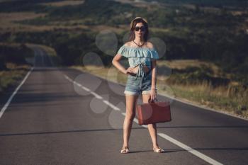 women is hailing a car on a road. Thumbing a ride. Outdoors vacation..