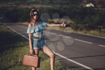 women is hailing a car on a road. Thumbing a ride. Outdoors vacation..