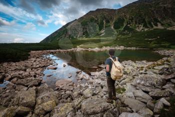 Man Traveler with backpack near mountain lake . Travel Lifestyle concept. Travel and active life concept with team. Adventure and travel in the mountains region in the Poland Tatri