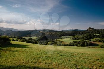 Summer mountain landscape in Slovakia. meadows with green grass, mountains, blue sky with clouds and sun. Highway in fields. Trip in europe. Travel