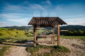 Summer mountain landscape in Slovakia. meadows with green grass, mountains, blue sky with clouds and sun. Highway in fields. Trip in europe. An arbor at a mountain viewpoint