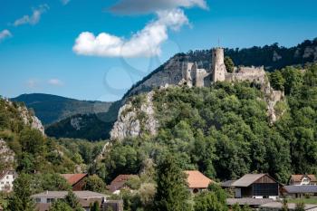 romantic castle on top of a hill in a mountainous valley in the Alps of Switzerland with a blue sky in the background, small village under the rock