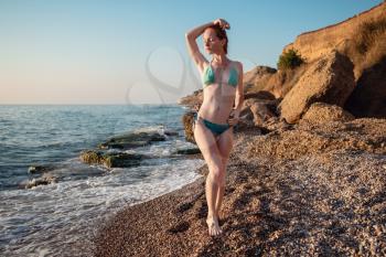 Sexy young girl in swimsuit posing on the beach. Beautiful ginger woman relaxing at the ocean. Concept of sporty model, swimwear