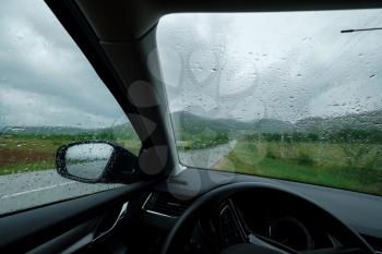 Driving car in the rain on wet road. Rainy weather through the car window. Rain through wind-screen of car. View through the car window in the rain. natura background